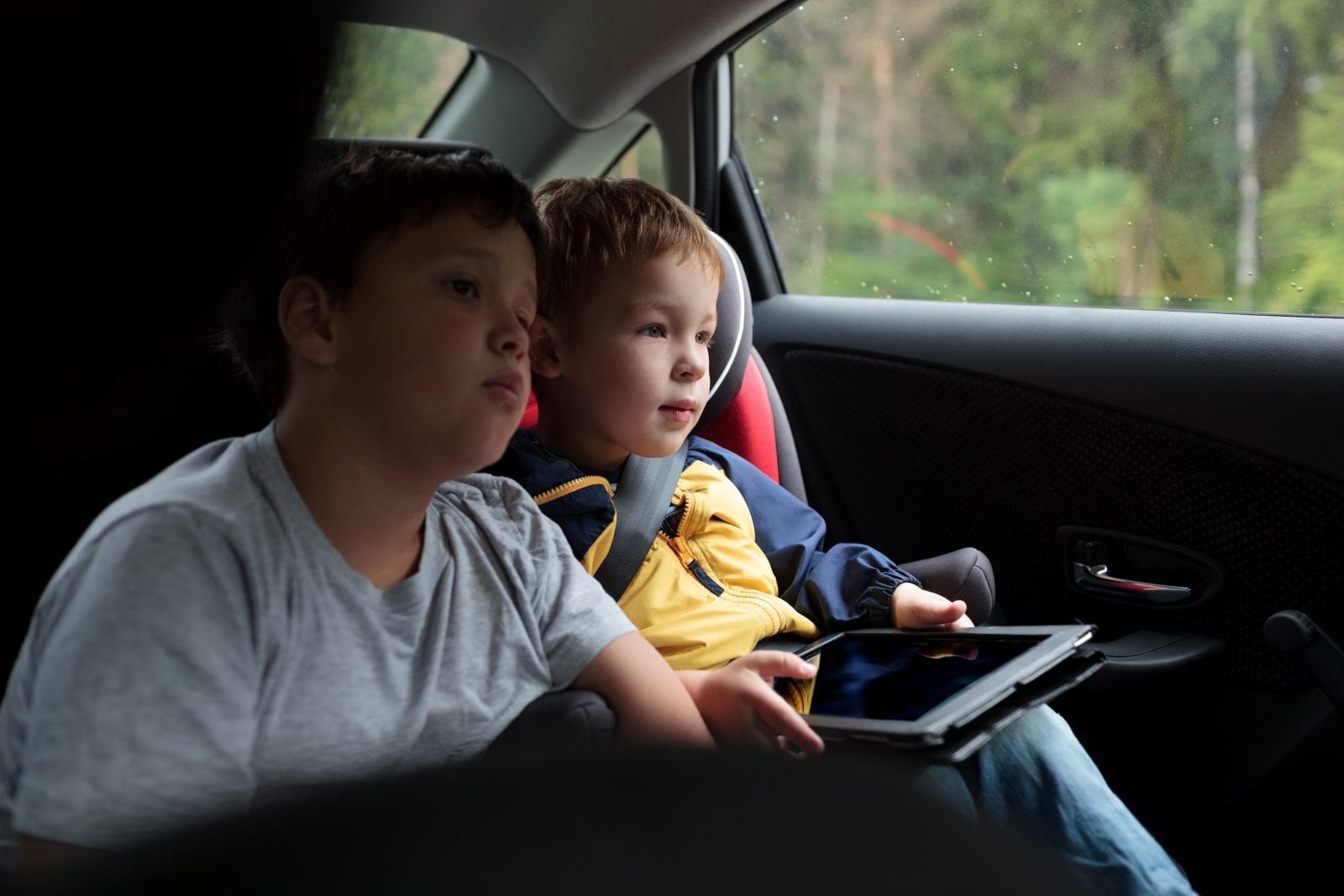 two kids in car on ipad