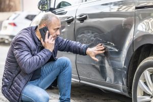 man checking scratches on his car and removing them
